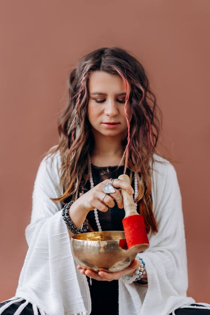 Meditative woman using a Tibetan singing bowl for wellness and relaxation.